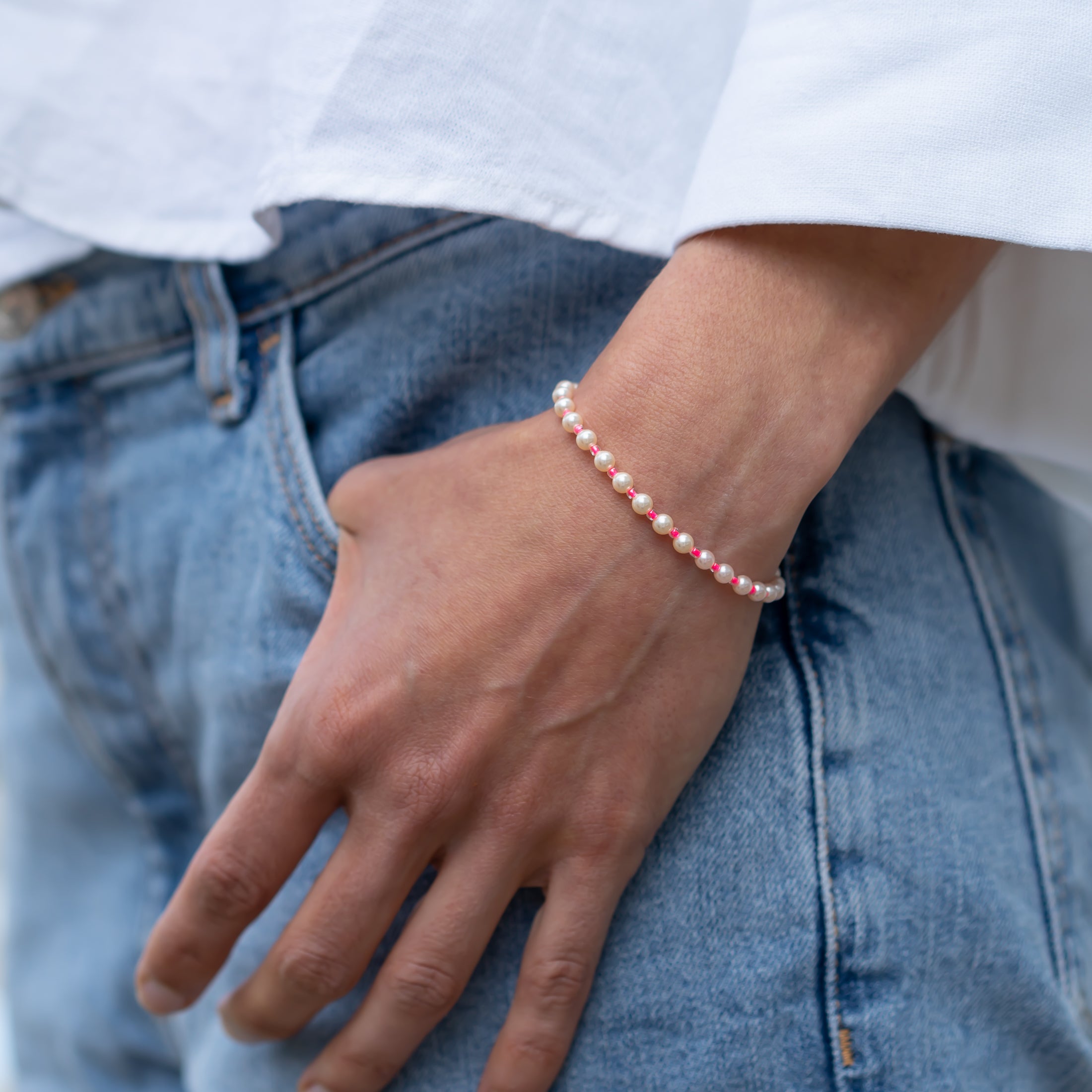 Handgemachtes pinkes Perlenarmband aus recyceltem 14K Gold an Damenhand, kombiniert mit blau-weißem Jeansstoff und weißem. - Perlenarmband Rebell in luminous pink, orange, blau, rosa oder goldgelb - Apricot/Orange, Blau, Gelb, Pink