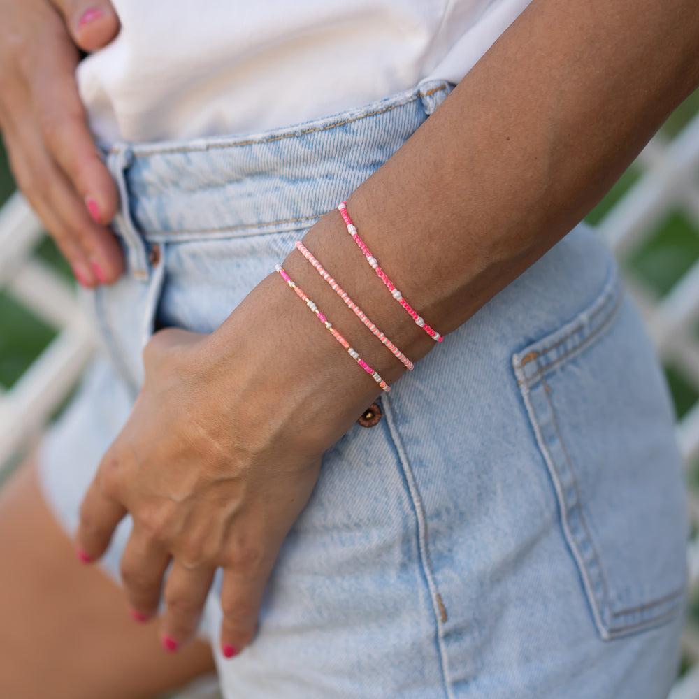 Handgemachtes pinkes Armbandset aus feinen Perlen, zart und luftig am Damenhandgelenk getragen, kombiniert mit Denim-Shorts. - Armbandset Karibik - Pink
